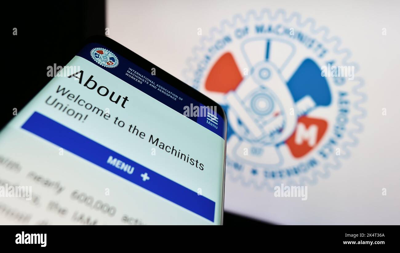 Smartphone with website of American-Canadian trade union IAM on screen in front of logo. Focus on top-left of phone display. Stock Photo