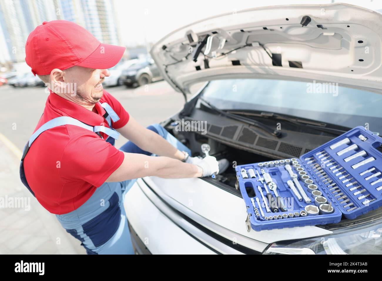 A man on street fixes a breakdown in a car with a wrench Stock Photo ...