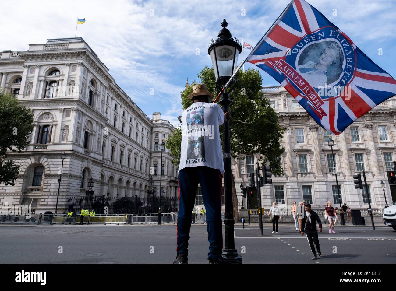 Man waving a Union flag depicting the face of Queen Elizabeth II as people gather in Westminster as Liz Truss, winner of the Conservative Party leadership race begins her tenure as Prime Minister on 6th September 2022 in London, United Kingdom. As new PM, Truss will have many key issues to deal with especially the cost of living crisis and increasing fuel bills. Stock Photo