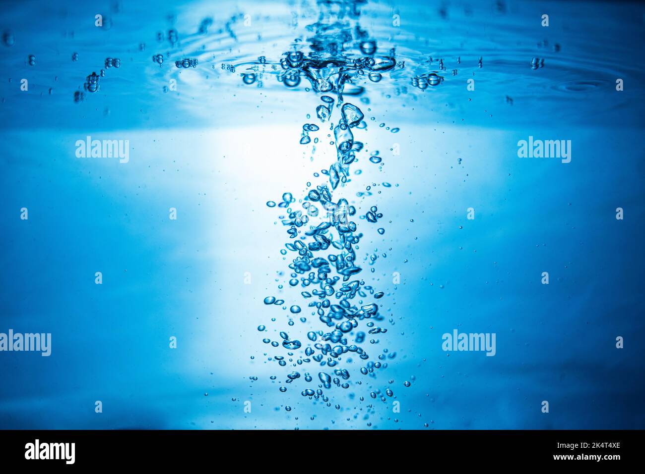 An abstract background created by air bubbles in water under blue lighting. Stock Photo