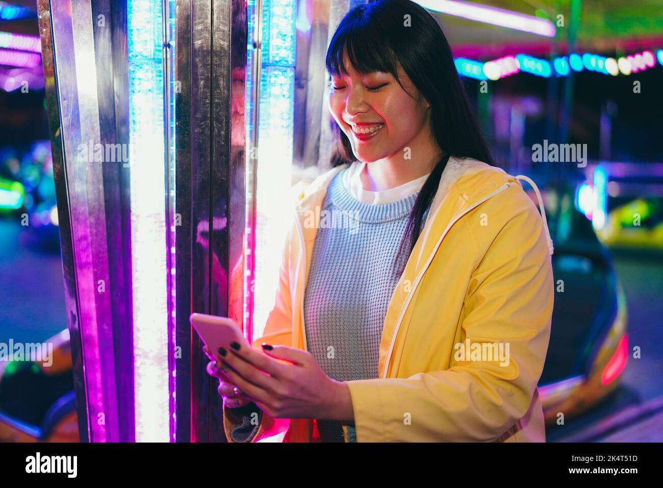 Happy asian girl using mobile phone at amusement park Focus on face Stock Photo Alamy