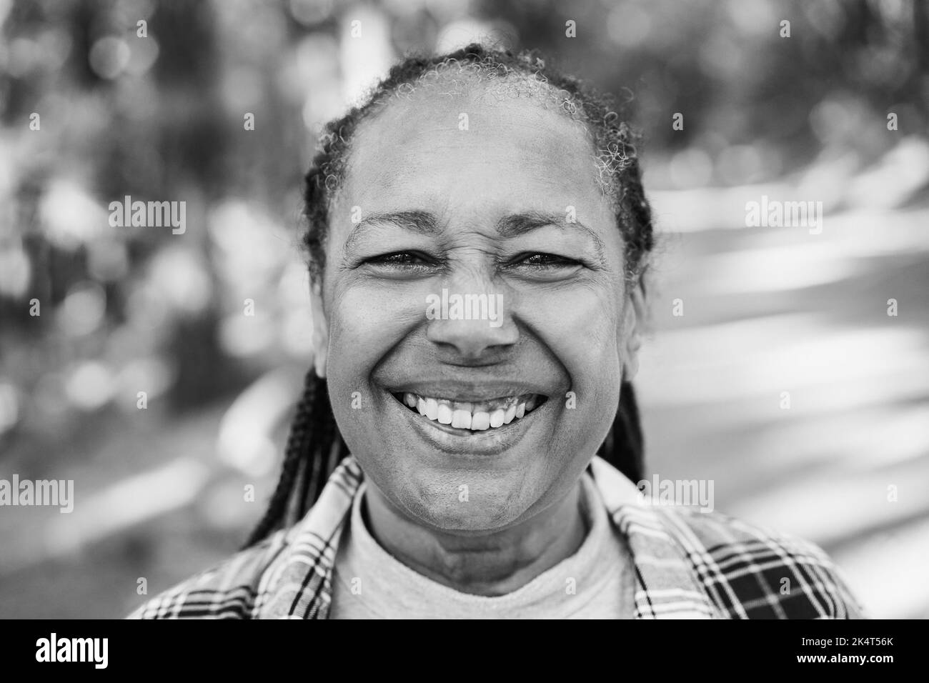 Portrait of african senior woman into the woods - Focus on eyes - Black and white editing. Stock Photo