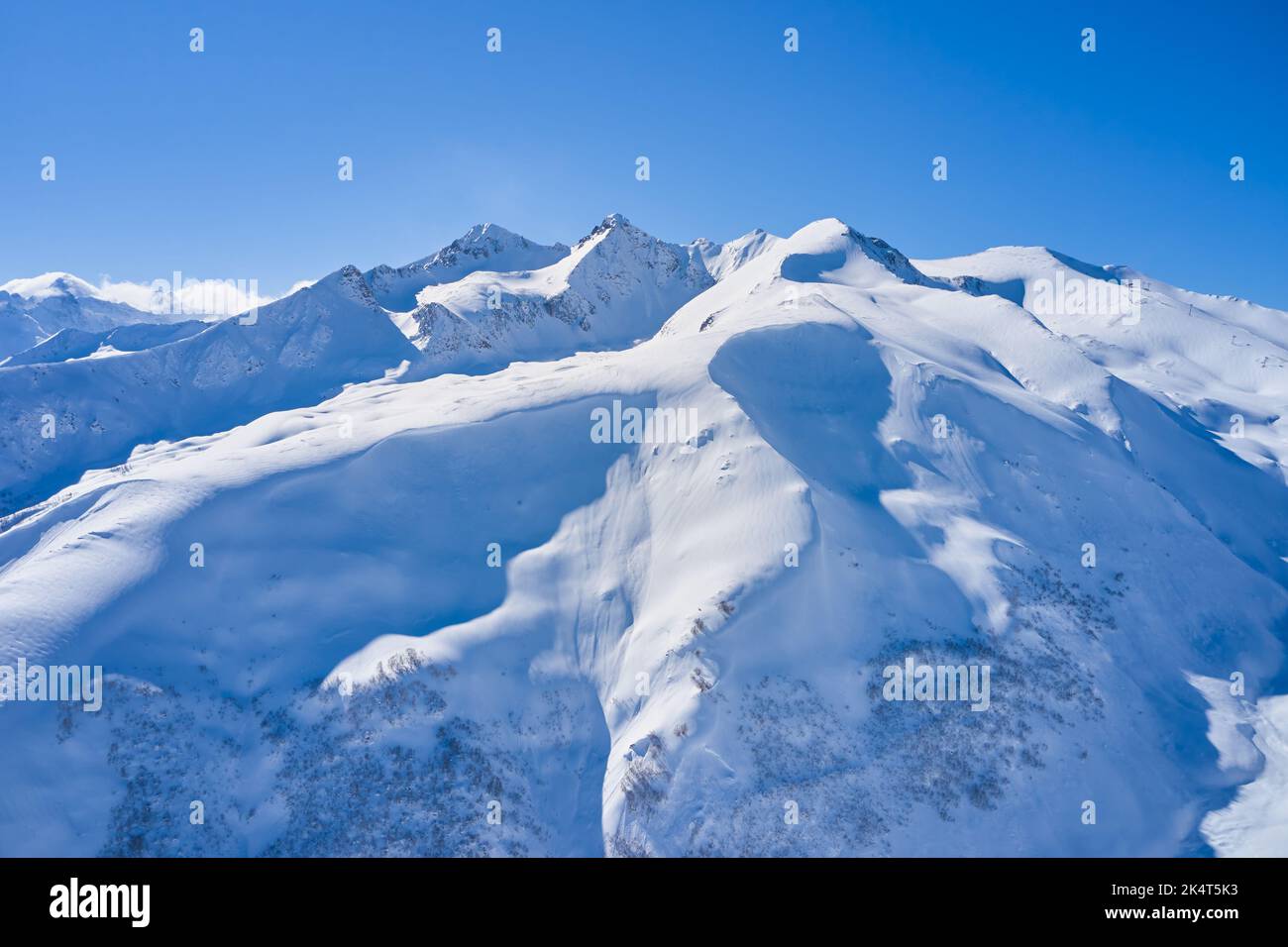 Aerial view of snowy mountains on a sunny day. Stock Photo