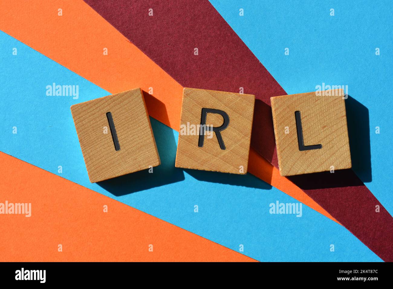 IRL abbreviation for In Real Life in wooden alphabet letters isolated on background, phrase meaning not online or in chat Stock Photo