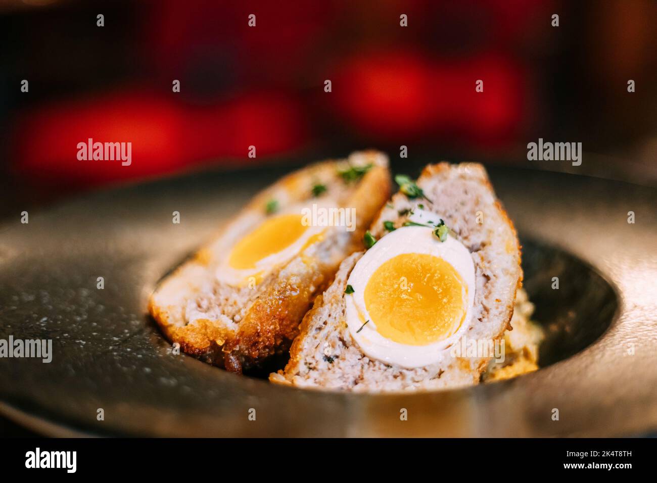 Traditional Scotch egg . Skirly is fried oatmeal with onions and spices, a classic garnish of Scotland. Honey mustard sauce. Traditional cuisine of Stock Photo