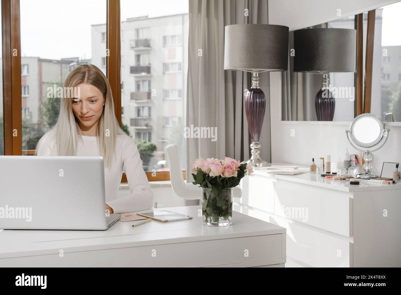 Woman works at the reception in a beauty salon. Typing something on laptop and talks on the phone with client, making appointments in studio Stock Photo