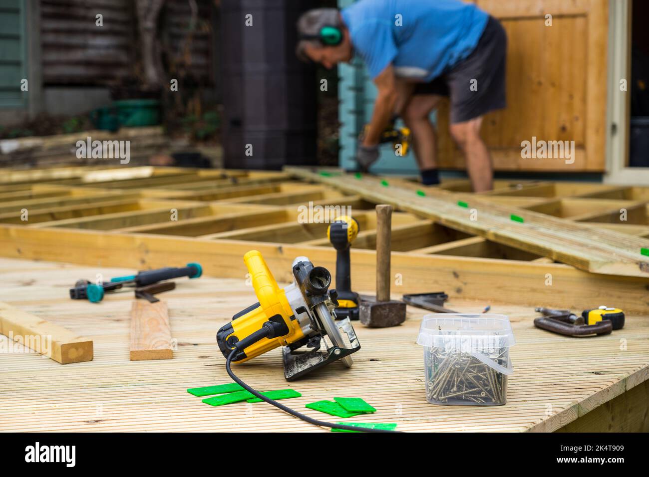 Man constructing a deck, showing decking joists, planks and deck tools Stock Photo