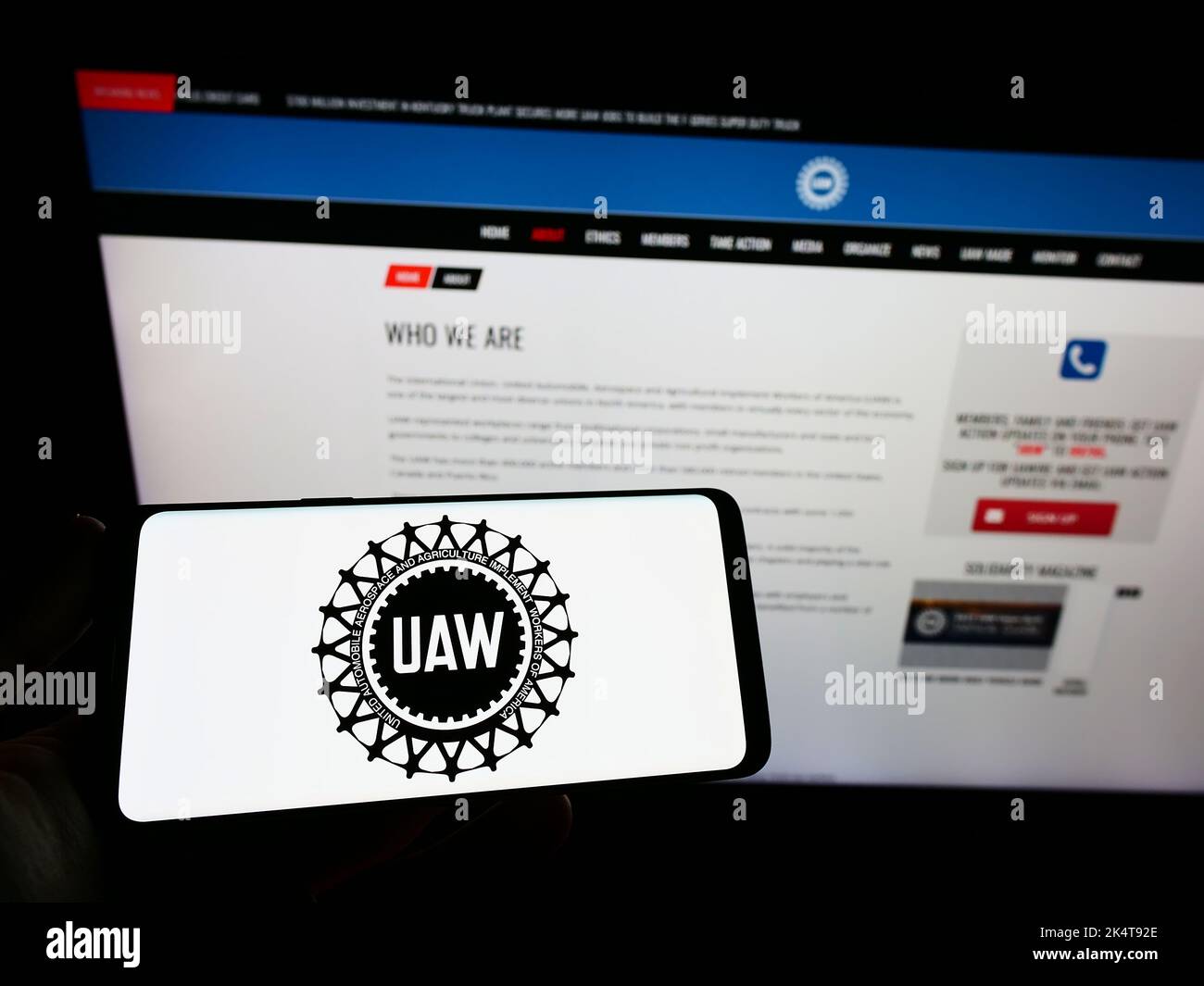 Person holding smartphone with logo of US trade union United Auto Workers (UAW) on screen in front of website. Focus on phone display. Stock Photo