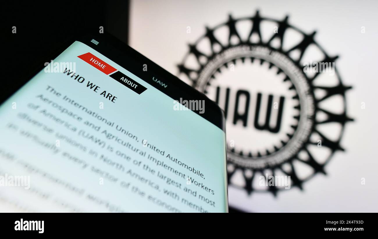 Mobile phone with website of US trade union United Auto Workers (UAW) on screen in front of logo. Focus on top-left of phone display. Stock Photo