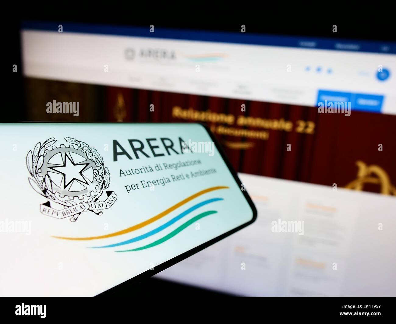 Mobile phone with logo of Italian regulation authority ARERA on screen in front of website. Focus on phone left of display. Stock Photo