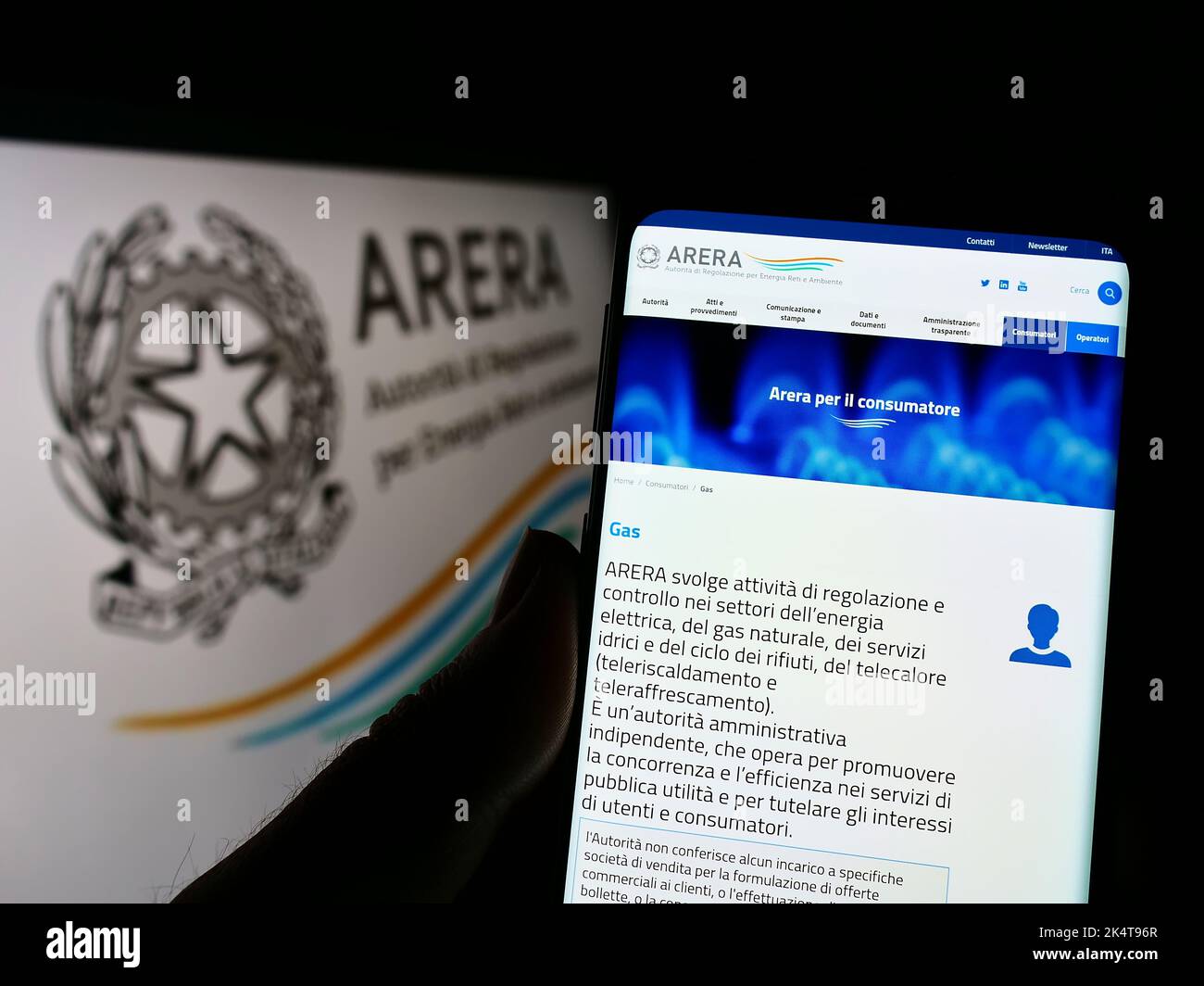 Person holding cellphone with webpage of Italian regulation authority ARERA on screen in front of logo. Focus on center of phone display. Stock Photo