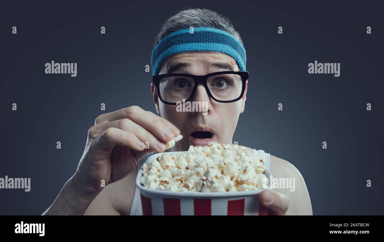 Funny guy with glasses and headband watching movies, he is staring at