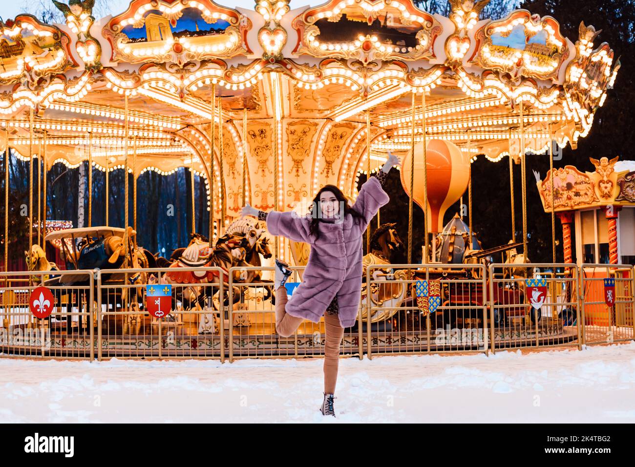 A young girl jumps around a French carousel in an amusement park in ...