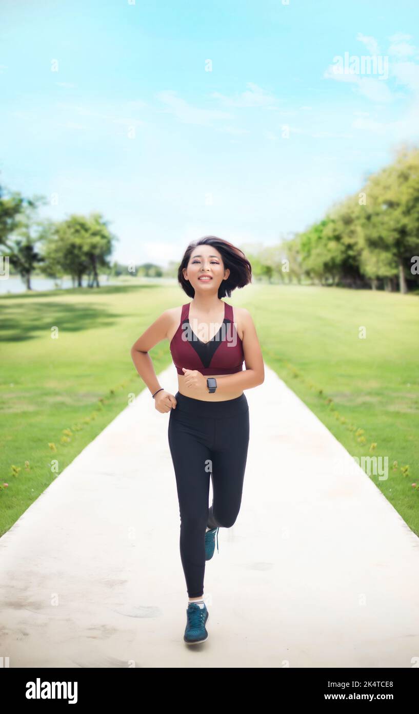 asian woman jogging in day light at park for good health Stock Photo
