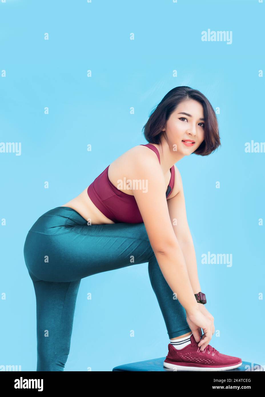 Asian woman model in sport suite pulling shoelaces taut on isolated background for advertize banner (include path) Stock Photo