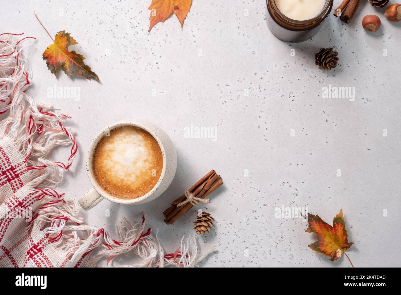 Autumn composition. Cup of coffee, blanket, autumn leaves, cinnamon sticks on white background. Stock Photo