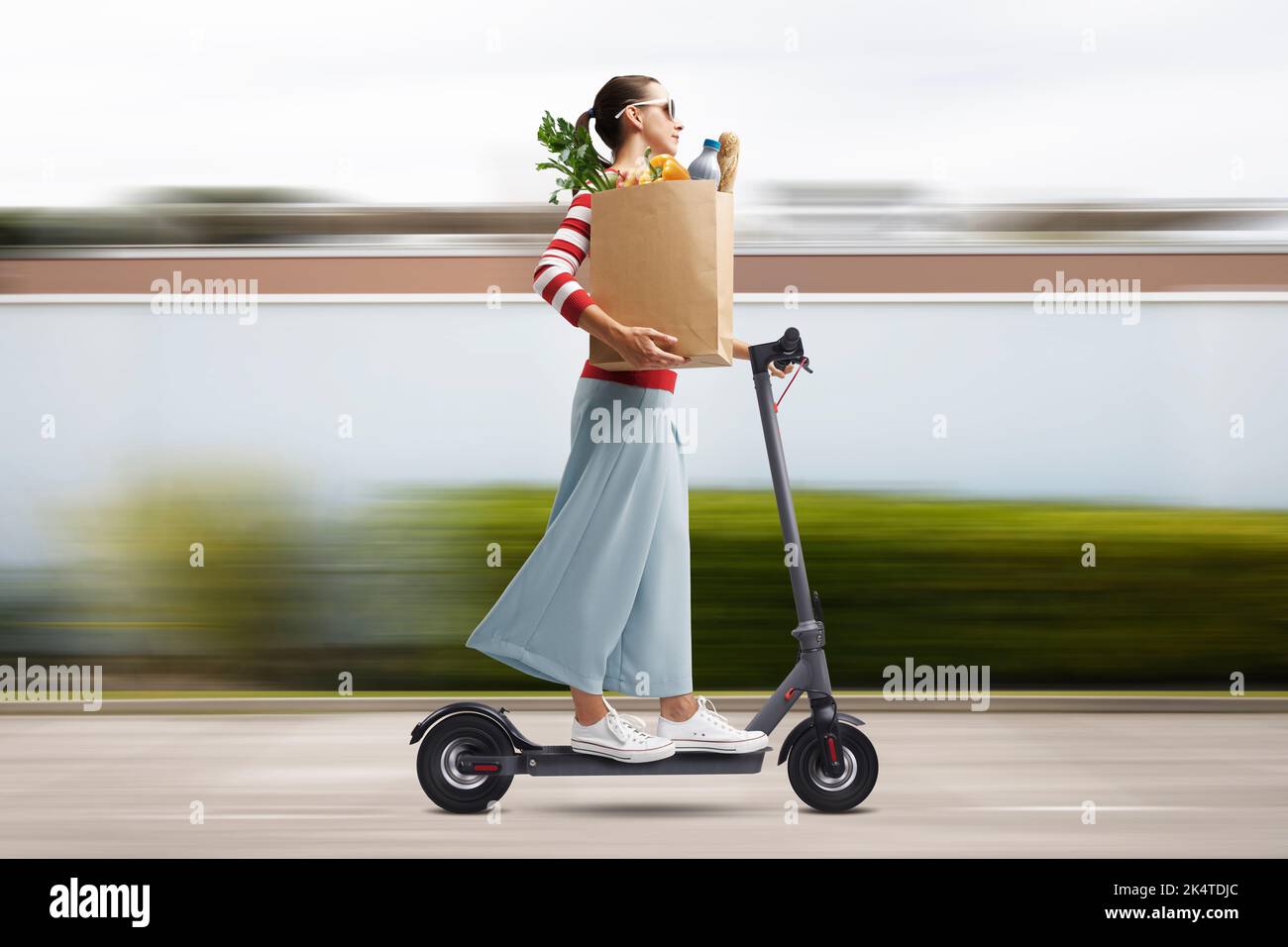 Young woman carrying a paper bag with groceries and riding a fast