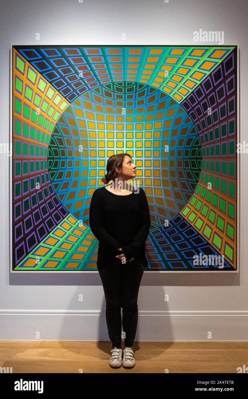London, UK.  4 October 2022. A staff member with 'Einstein-Ker', 1976, by Victor Vasarely at a preview of “Einstein in the Sky with Diamonds”, a new exhibition by the late Hungarian artist Victor Vasarely.  A selection of eight major works by the master of optical and kinetic art, covering almost his entire career from the 1950s to the 1980s are on show at Mazzoleni gallery in Mayfair 12 October to 16 December 2022.  Credit: Stephen Chung / Alamy Live News Stock Photo