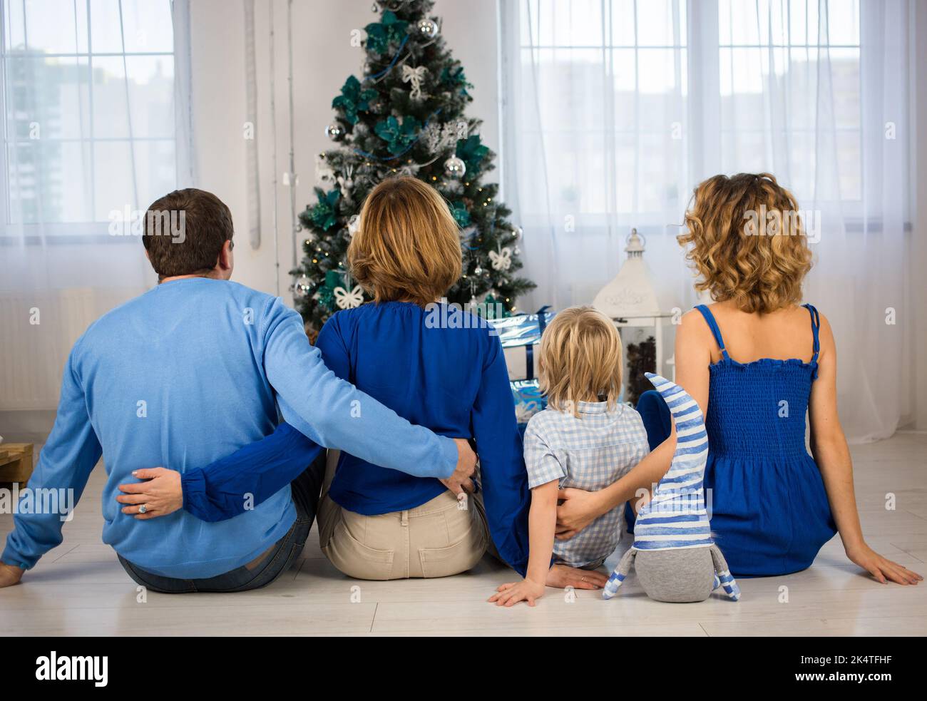 Happy new year. Christmas with family. Rear view of parents, little son, daughter. Dressed in shades of blue. concept of friendly relations, unity, su Stock Photo