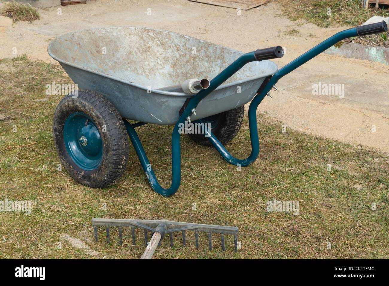 Wheelbarrow in the garden. agricultural working. rake lies on the
