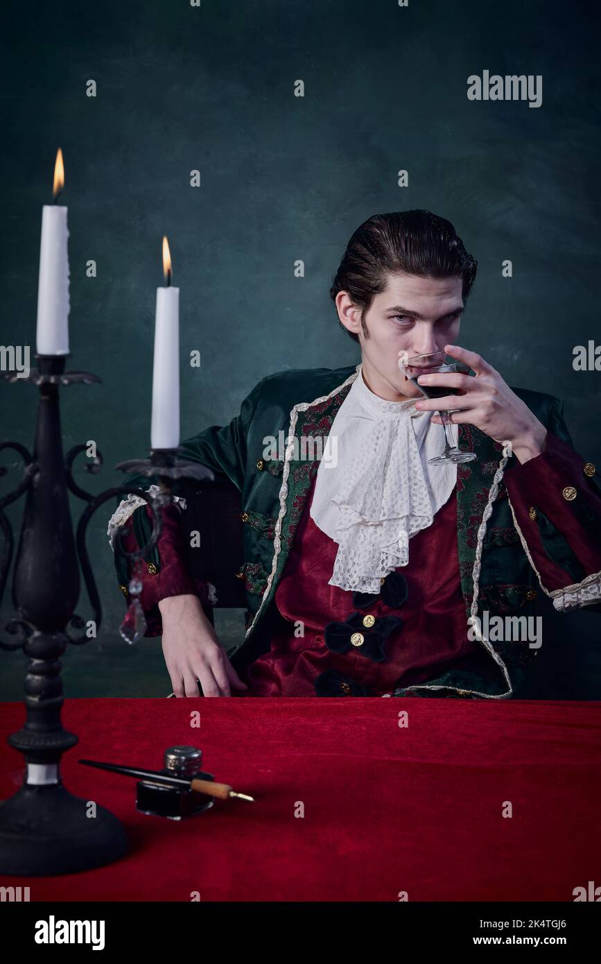 Portrait of terrifying man in image of vampire, Dracula drinking blood