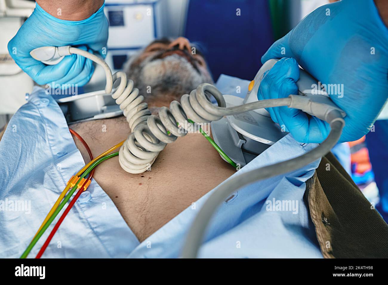 Ambulance worker using portable defibrillator in attempt to revive senior man inside ambulance