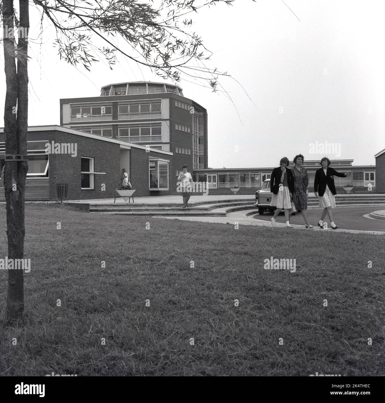 1964, historical, two female pupils with their mother outside  The Manderville school, a modern built secondary or high school in Aylesbury, Buckinghamshire, England. UK. Stock Photo