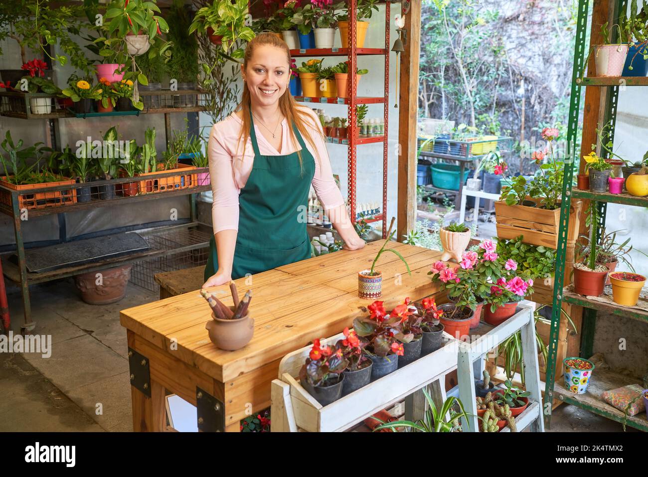 Friendly young woman working as a florist and specialist salesperson in the nursery's flower shop Stock Photo