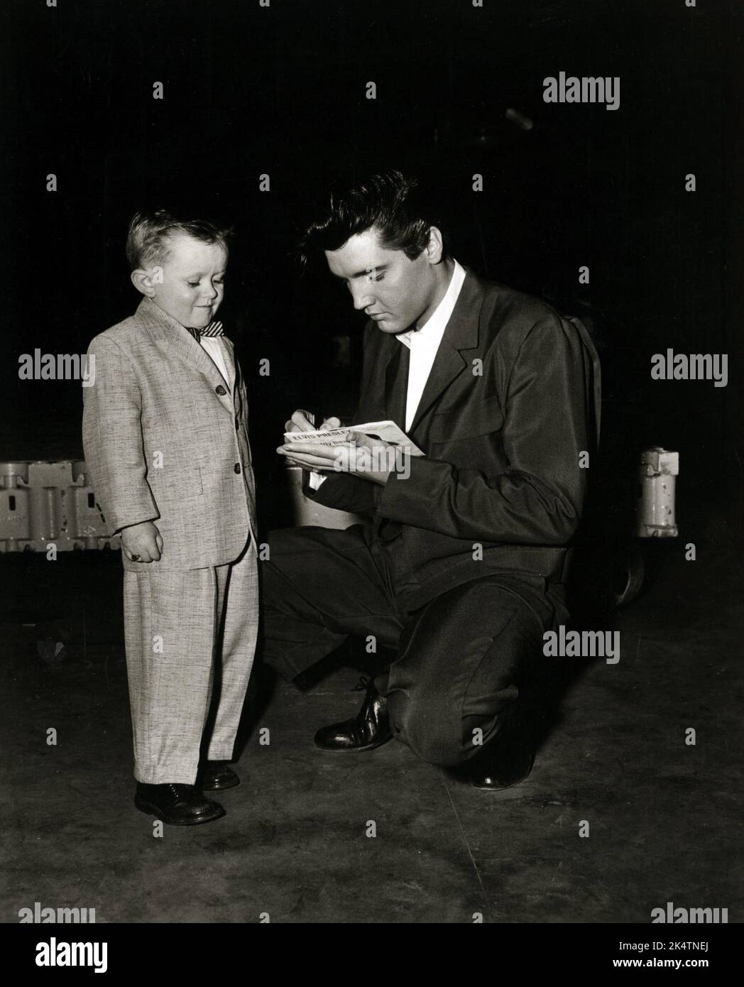 Elvis writing autograph for a young fan. Elvis is signing his name on the single release of Teddy Bear. Tuesday February 4, 1958. Stock Photo