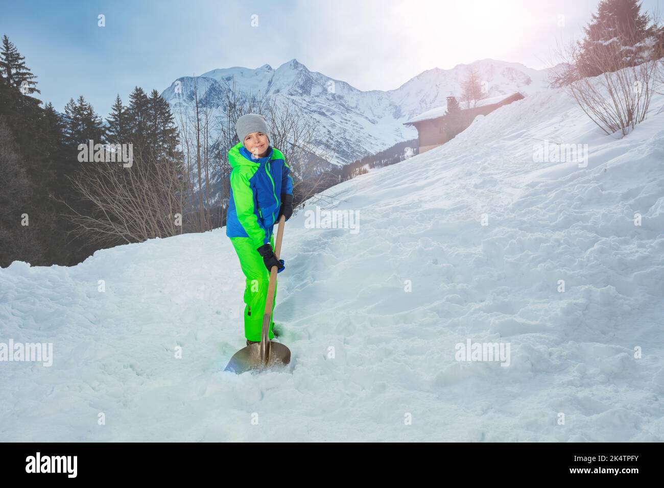 Boy clean path from snow at country house over Alps mountains Stock Photo
