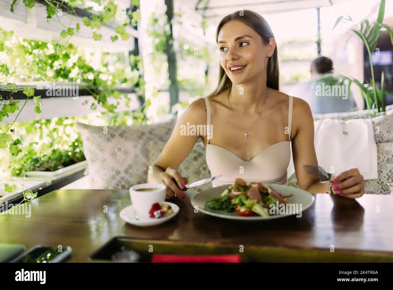 Smiling woman eating fresh salad in restaurant Stock Photo
