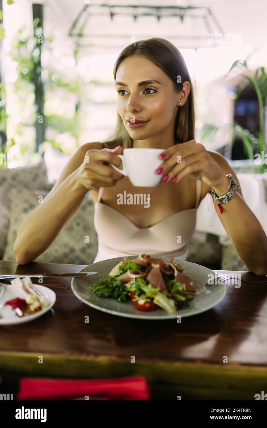 Portrait of young smiling woman having a breakfast or lunch in a cafe Stock Photo