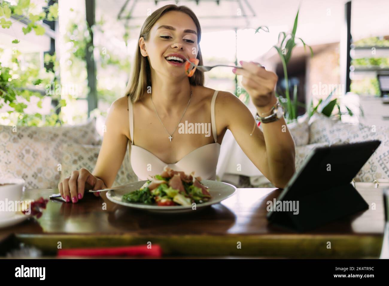 eating, technology, people and leisure concept - happy young woman with tablet pc computer and food listening to music at restaurant Stock Photo