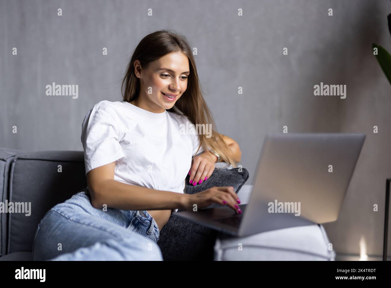 Joyful woman holds the credit card, shopping online, online payment using laptop, sitting at living room Stock Photo