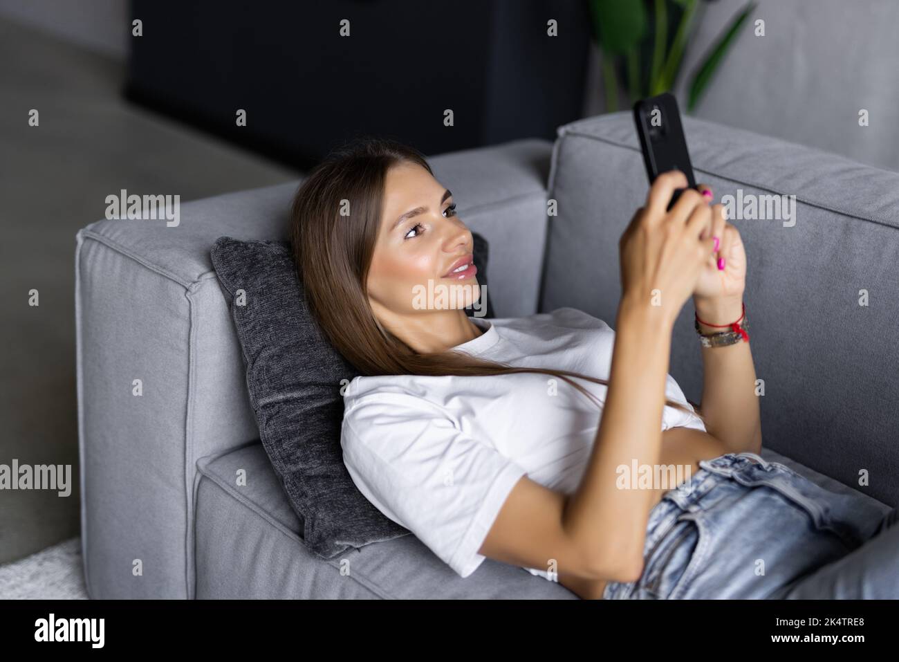 Excited woman watching media content on line in a mobile phone sitting on a couch in the living room Stock Photo
