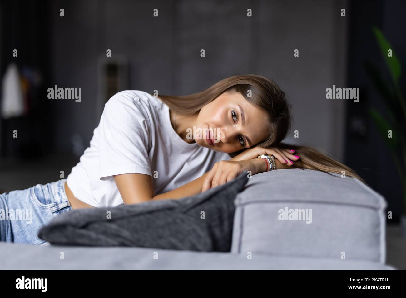Smiling pretty woman wearing casual clothes relaxing on a couch at home Stock Photo