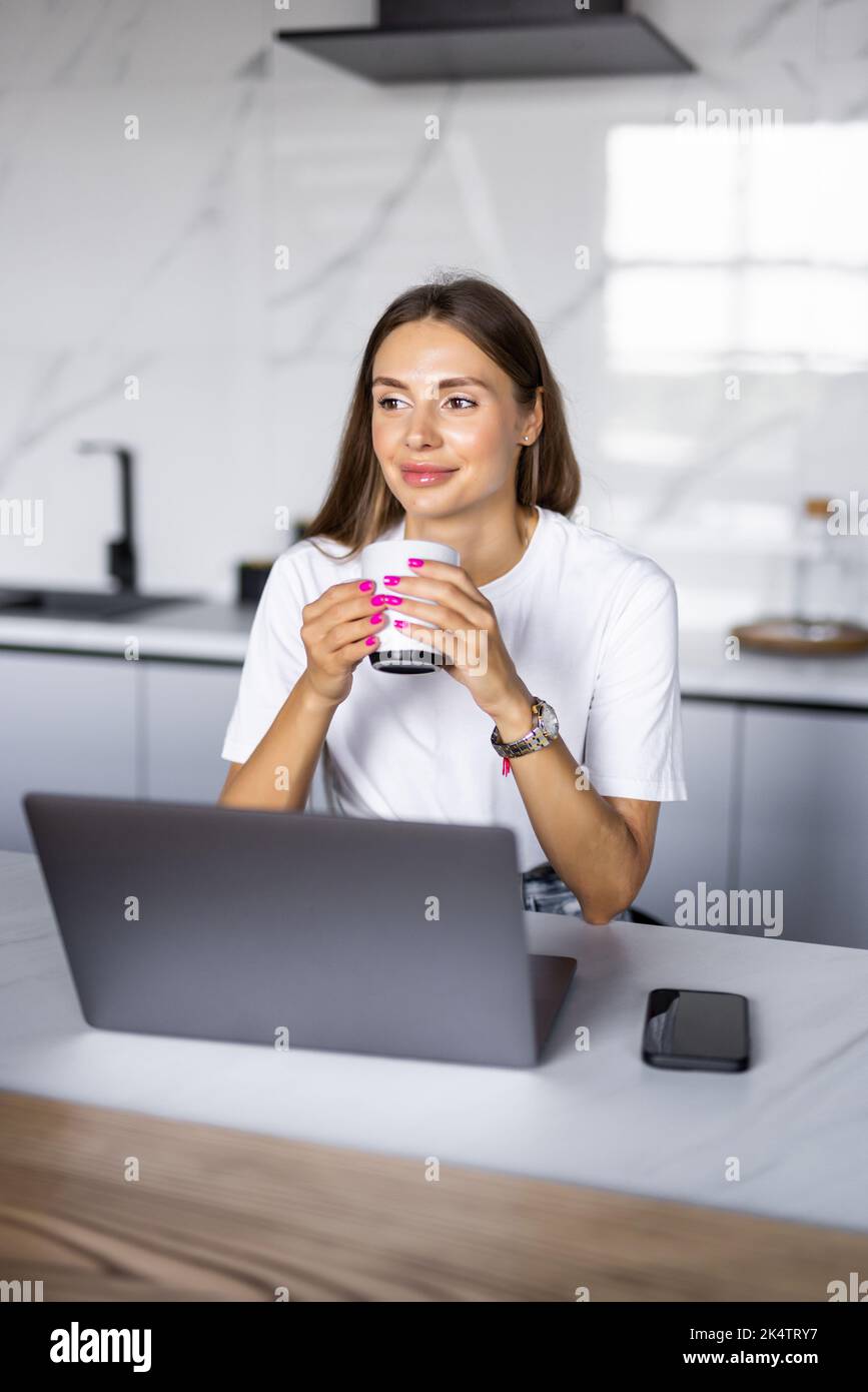 Young happy woman drinking coffee on the kitchen in the morning. Stock Photo