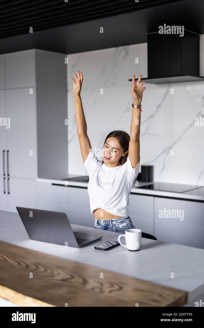 Excited woman freelancer raise hands up scream hooray in delight celebrate finish work on difficult project. Stock Photo