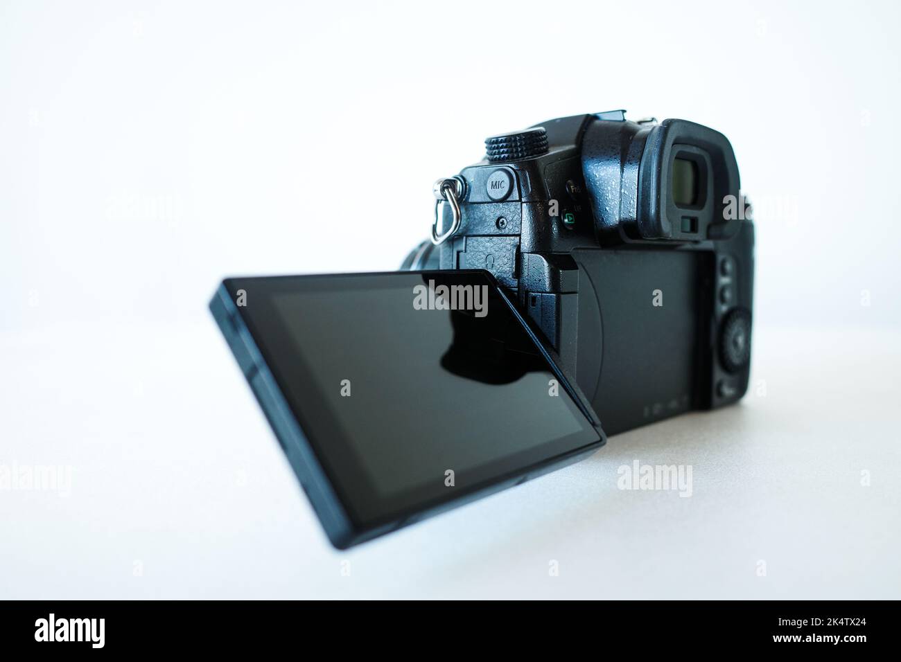 Flip out screen of modern mirrorless camera on white background Stock