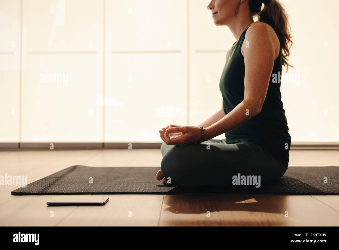 Mature woman meditating while sitting in easy pose. Senior woman doing a breathing exercise during a session of hatha yoga. Woman following a healthy Stock Photo