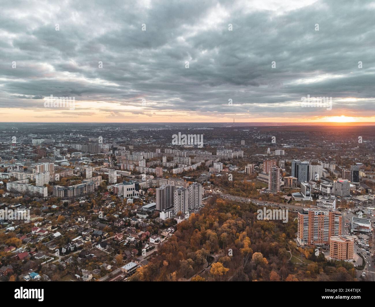 Aerial autumn city park sunset view with epic cloudscape. Botanical garden and Kharkiv city center. Residential district buildings in evening light Stock Photo
