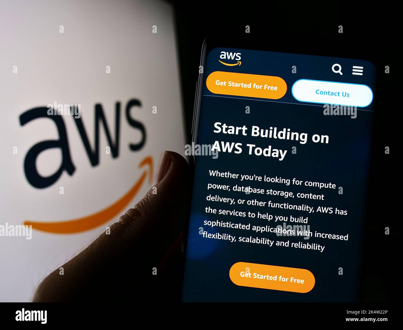 Person holding cellphone with website of US cloud company Amazon Web Services Inc. (AWS) on screen with logo. Focus on center of phone display. Stock Photo