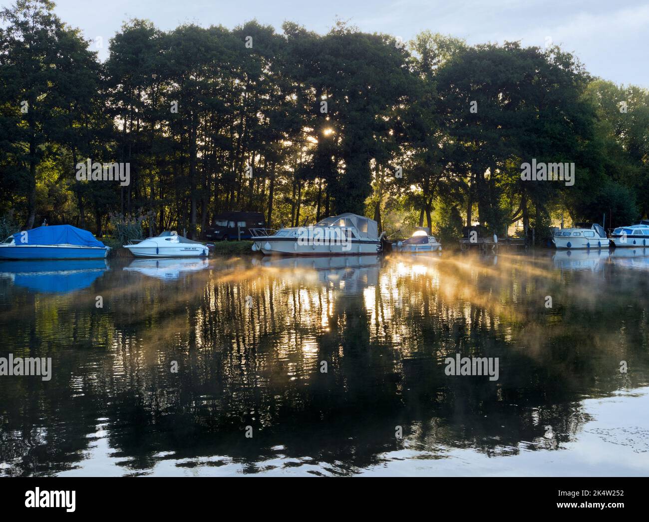 Here we see a line of pleasure boats moored by the Thames by Kennington, just outside Oxford. It's a misty Autumn sunrise. Seen from Thames Path - a w Stock Photo