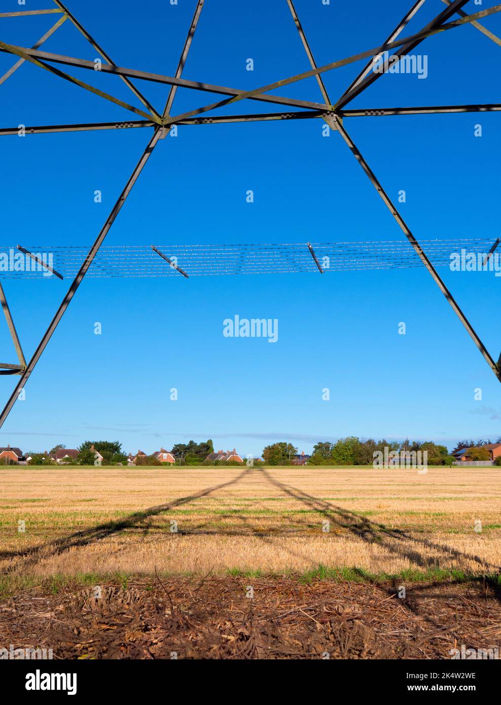 I love electricity pylons; I find their abstract, gaunt shapes endlessly fascinating. Here we see shadows cast by a large pylon in a field in rural Ra Stock Photo