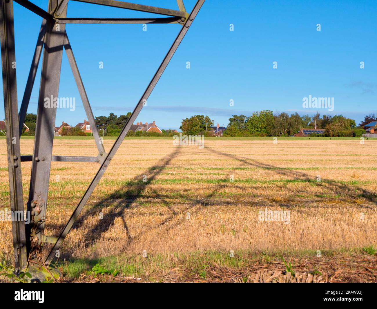 I love electricity pylons; I find their abstract, gaunt shapes endlessly fascinating. Here we see shadows cast by a large pylon in a field in rural Ra Stock Photo