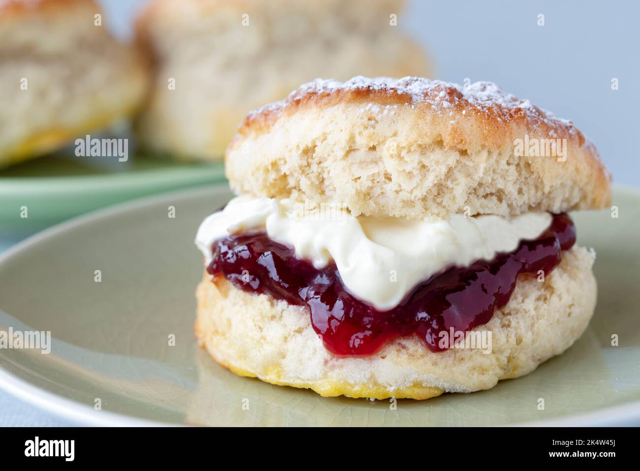 A fresh traditional English home made scone. The cake is split and filled with jam and topped with thick clotted cream. A delicious Cornish cream tea. Stock Photo