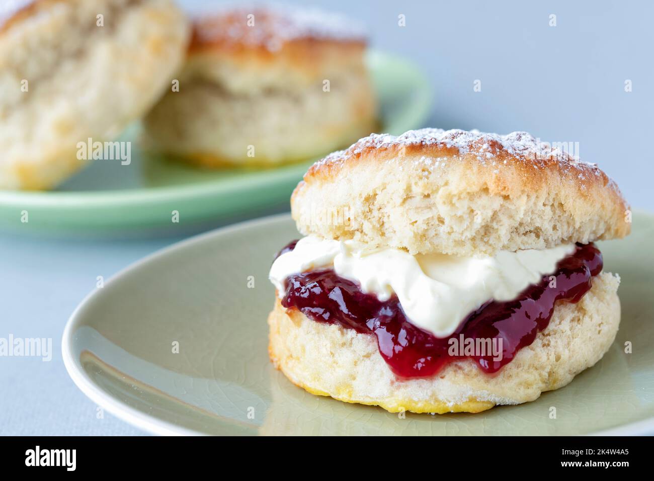 A fresh traditional English home made scone. The cake is split and filled with jam and topped with thick clotted cream. A delicious Cornish cream tea. Stock Photo