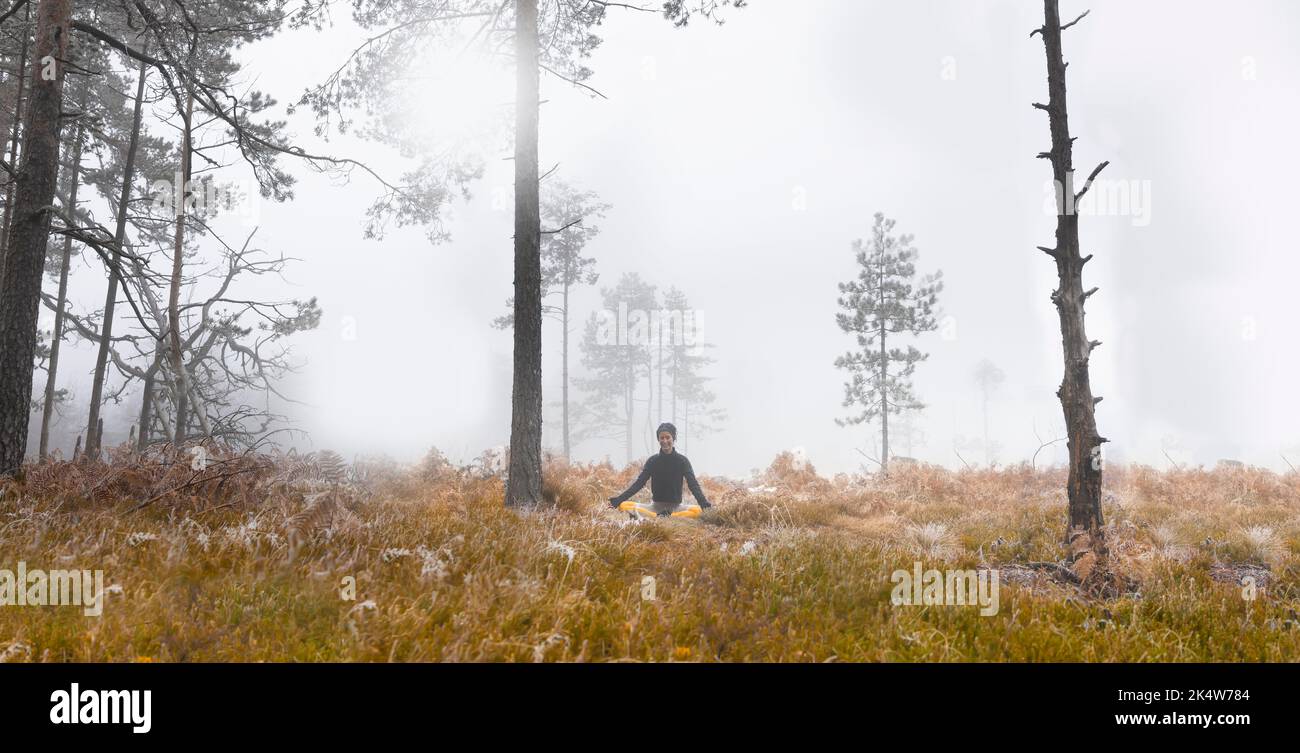 A woman finding her inner peace while meditating in the forest Stock Photo