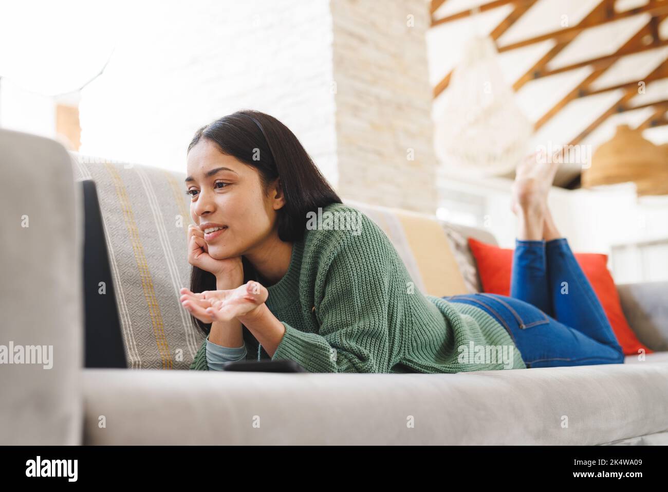 Happy biracial woman laying on sofa in living room, using laptop Stock ...