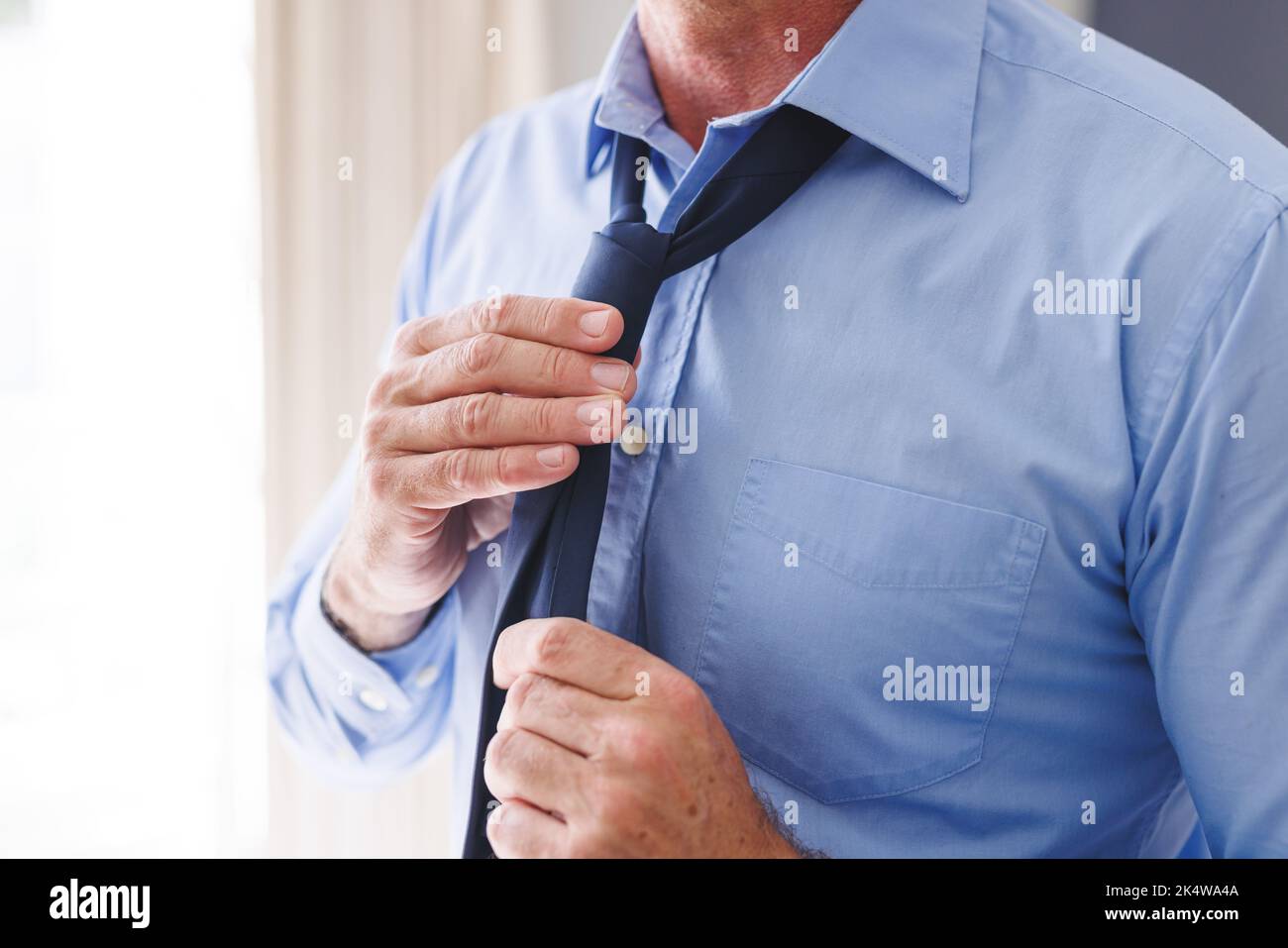 Midsection of caucasian man standing in bedroom, tying a tie Stock ...